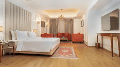 A suite featuring a large bed, a living area, elegant wooden floors, and modern decor – Sarovar Premiere, Srinagar.